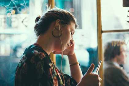 A photo of a woman with earphones in her ears while seeming to contemplate about something